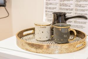 a tray with two mugs and a coffee pot on it at Apartments Nuhi in Ulcinj
