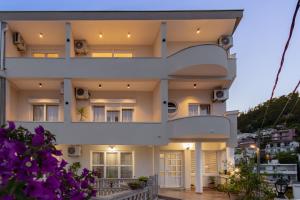 a white building with balconies and purple flowers at Apartments Nuhi in Ulcinj