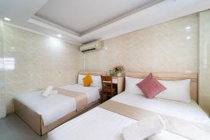 two beds in a small room with white and pink pillows at Ngân Hà Bouitque Apartment-Hotel in Ho Chi Minh City