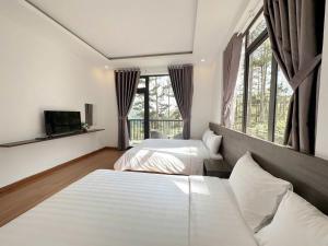 a bedroom with two beds and a tv and windows at Mimosa Forest Hotel Villa in Xuan An +44 photos