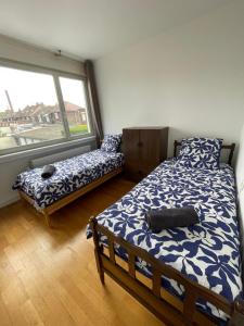 a bedroom with two beds and a large window at Appartement entier Velodrome in Roubaix