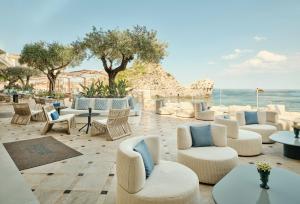 a patio with white chairs and tables and the ocean at Mazzarò Sea Palace - The Leading Hotels of the World in Taormina