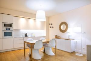a kitchen with white cabinets and a wooden table and chairs at Praia do Sal Resort & SPA in Alcochete
