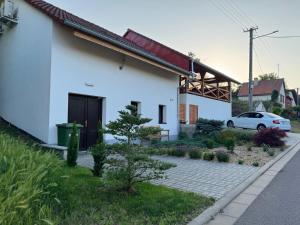 a white house with a car parked next to it at Apartmán Sebina s vinným sklípkem in Drnholec