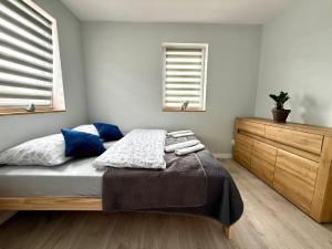 a bedroom with a bed and a dresser and two windows at Chabrowy Domek in Jeżów Sudecki