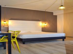 a bedroom with a bed and a table and a yellow chair at ibis styles Trani in Trani +72 photos