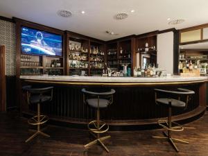 a bar with two stools and a tv in a room at Mercure Hotel Frankfurt Airport Langen in Langen