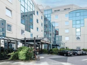 a large building with cars parked in a parking lot at Mercure Hotel Frankfurt Airport Langen in Langen