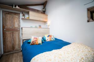 a bedroom with a blue bed with two pillows at P'tite Maizoun - Gîte in Hermanville-sur-Mer