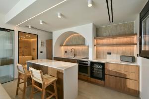 a kitchen with a island with chairs and a sink at Ciel Seafront Suites - Lefkada in Lygia