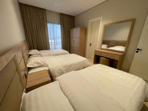 a hotel room with three beds and a mirror at شقة O&Me الفندقية in Medina