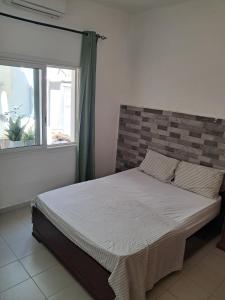 a bedroom with a bed with a brick wall and a window at Rdc in Ouakam