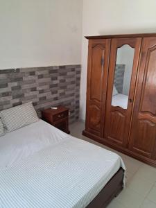 a bedroom with a bed and a wooden cabinet at Rdc in Ouakam