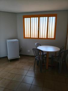 a dining room with a table and chairs and a window at Flats Rio Branco in Uberaba