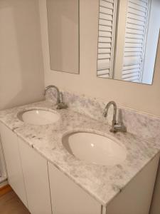 a bathroom with two sinks and a mirror at Flats Rio Branco in Uberaba