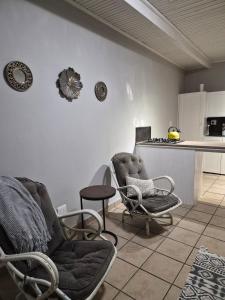 a living room with two chairs and a kitchen at 52 on 2nd Self-catering accommodation in Gonubie Park