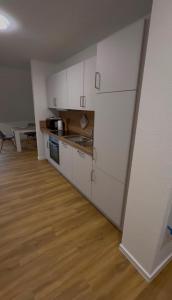 a kitchen with white cabinets and a wooden floor at Haus Bahnhofsblick in Ottersberg +7 photos