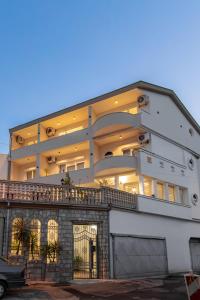 a large white building with a car parked in front of it at Apartments Nuhi in Ulcinj +48 photos