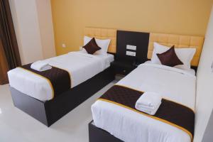 a hotel room with two beds with white and brown sheets at Hotel RAAGA INN in Tirupati