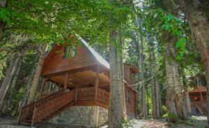 a cabin in the woods with a wrap around deck at Rest House in Oni +25 photos