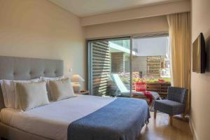 a bedroom with a bed and a large window at Praia do Sal Resort & SPA in Alcochete