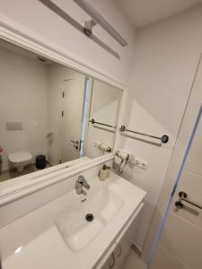 a white bathroom with a sink and a mirror at Sunset Beach Studio by Blaxy Resort Olimp in Olimp +25 photos
