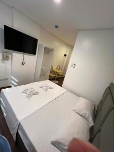 a bedroom with a white bed with a tv on the wall at LUNA by LCB Apartelle and Resort Tagaytay in Tagaytay