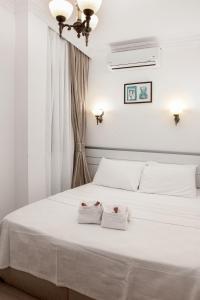 a white bedroom with two towels on a bed at Bozcaada Su otel in Bozcaada