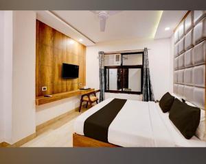 a hotel room with a bed and a television at Ganges Pride Hotel in Haridwār