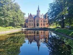 a large building with a reflection in a pond at Ryckevelde in Damme