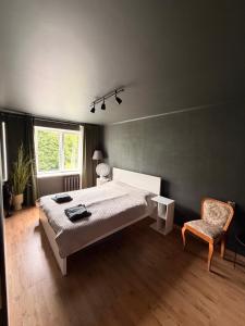 a bedroom with a bed and a chair and a window at Kauguri apartment residence in Jūrmala