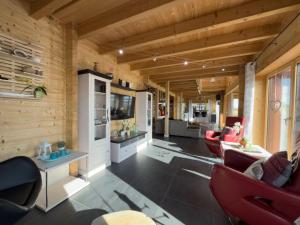 a living room with wooden walls and a room with red chairs at Haus Sina in Wangerland