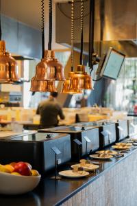 a kitchen with copper lights and plates of food at WestCord Hotel Eindhoven in Eindhoven +59 photos