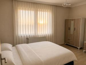 a bedroom with a large white bed and a window at Blue61 Residence Airport in Pelitli +2 photos