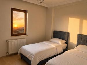 a bedroom with two beds and a window with the sunset at Blue61 Residence Airport in Pelitli