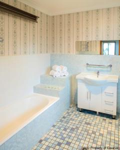 a blue bathroom with a tub and a sink at Echo Point Village in Katoomba