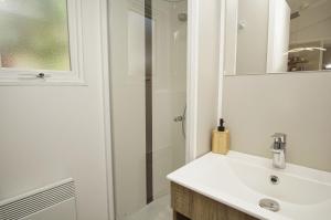 a bathroom with a white sink and a shower at Tiny Homes Nr 822 in Göhren