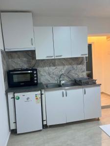 a kitchen with white cabinets and a sink and a microwave at Villa Utopia in Star Dojran