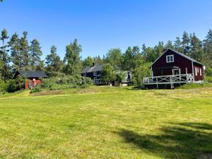 a red barn on a grassy field with trees at Villa Clara in Blankaholm