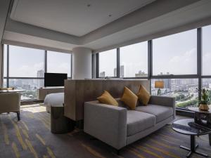 a living room with a couch and large windows at Pullman Suzhou Zhonghui in Suzhou