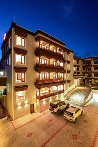 a building with two cars parked in front of it at Hotel Aero Ladakh in Leh