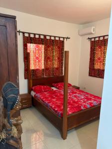 a bedroom with a bed with red sheets and red curtains at Villa Clémence in Mbour +33 photos