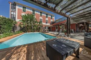 a pool with a table and chairs next to a building at SweetWater Villa - Pool - Solarium - Smart TV in Savona