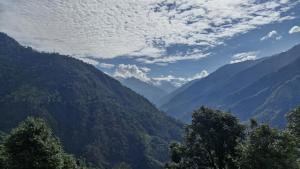 a view of a mountain valley with trees and clouds at The Captain's Quarters in Ukhimath +2 photos
