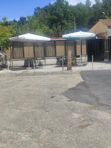a group of tables and umbrellas in a parking lot at O marco da legua&camino de santiago in Piñor