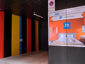 a exhibit with a bed in a room with colorful walls at ibis budget Bilbao City in Bilbao