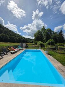 a swimming pool with blue water in a backyard with chairs and trees at Maison du bonheur in Gan