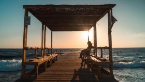 a woman sitting on a pier on the beach at Wadi Sabarah Lodge in Abu Dabbab