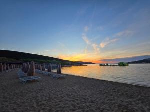 a beach with umbrellas and chairs and the water at Apartmani Kovač in Stara Novalja