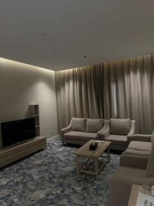 a living room with couches and a flat screen tv at فندق الفال الشمالي الفندقية in Ḑubā